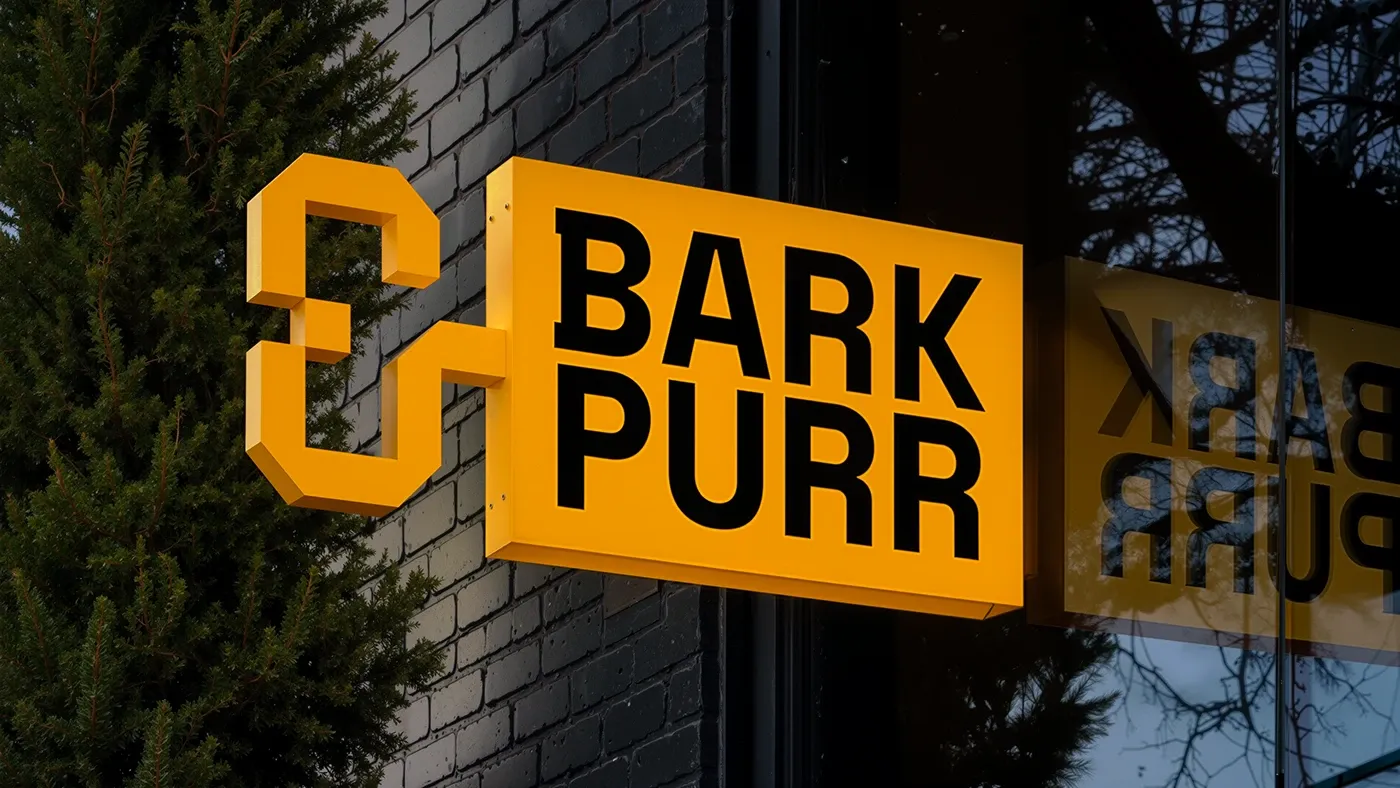 Yellow Bark & Purr storefront sign with an ampersand-shaped bracket on a dark brick wall