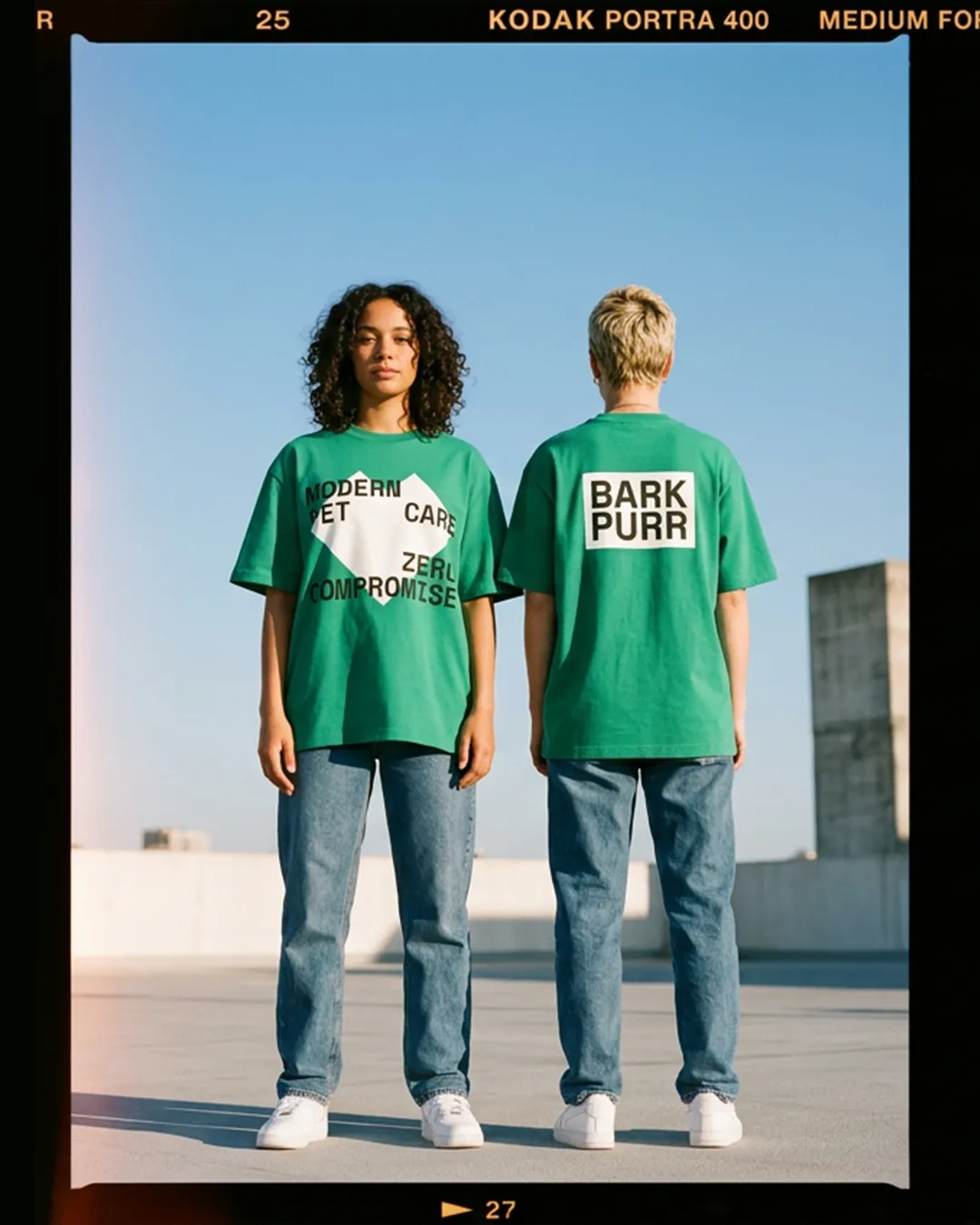 Two people on a rooftop in green Bark & Purr T-shirts reading "Modern pet care, zero compromise"